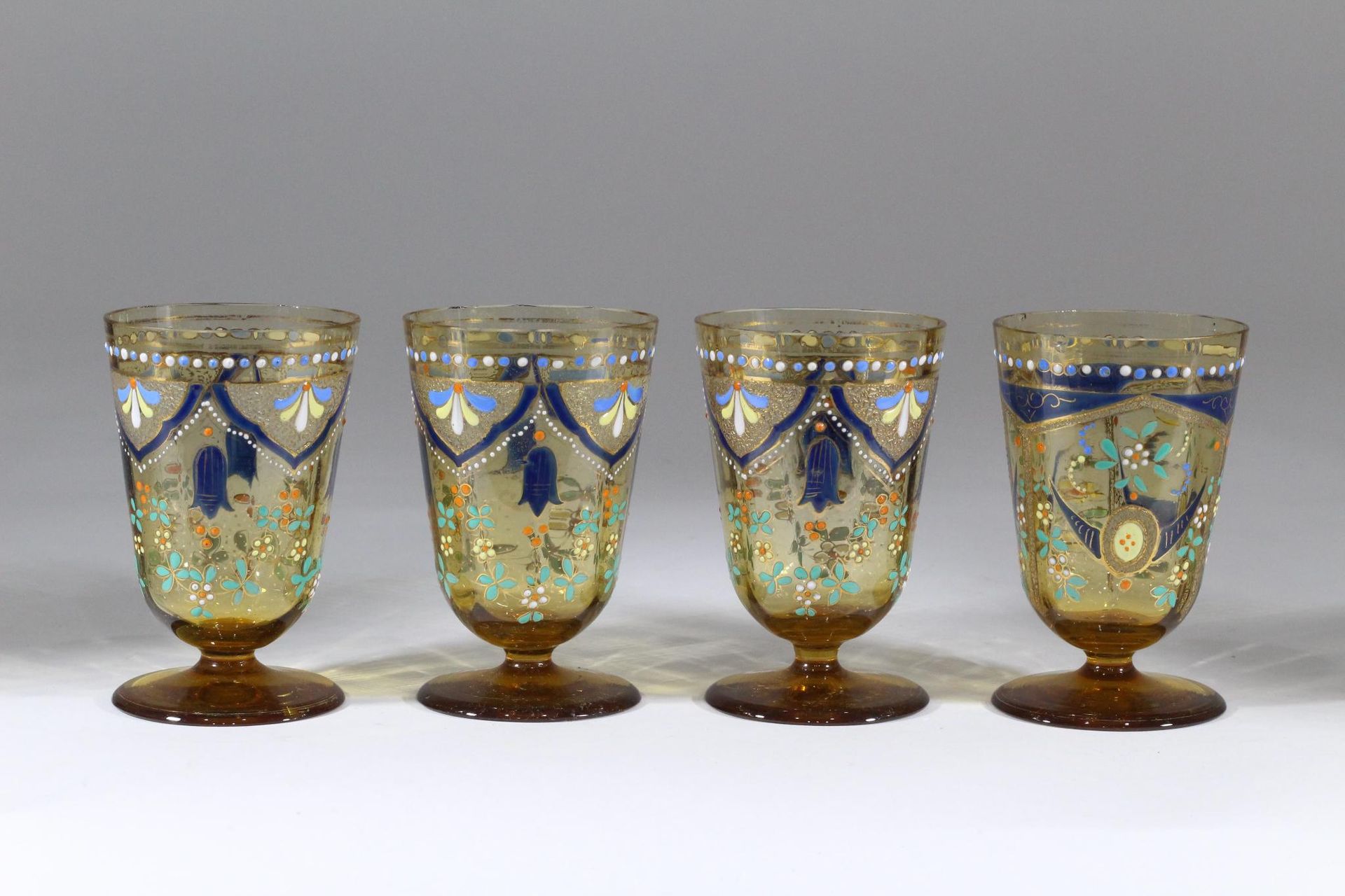 Null 四只琥珀色玻璃杯组套，杯身饰有多色珐琅装饰，包括半花、珍珠楣和造型叶片。 
十九世纪
其中一个款式略有不同，有一个小缺口。
高度高度：10.4 厘米