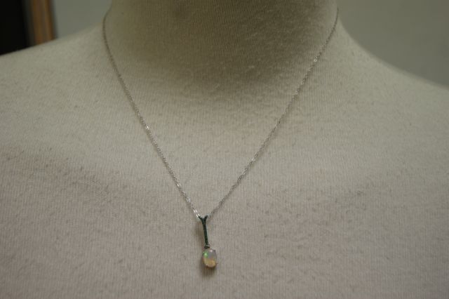 Null 925/1000细银项链，由一个梨形蛋白石为中心的吊坠组成

顶上有一排小绿宝石。

打开长度：约45厘米 重量：1.8克
