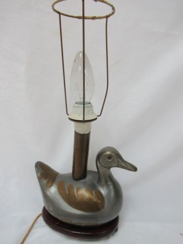Null 鸭子形状的锡制盒子，被安装成一盏灯，在一个木质底座上，27厘米。缺少一只脚。约1980年。