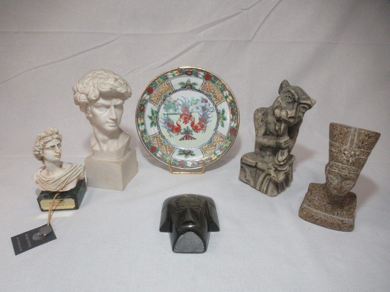 Null 一批旅行纪念品，包括：一件埃及石雕、一件墨西哥黑曜石头像、三件石膏像和一件中国盘子。尺寸从 9 厘米到 14 厘米不等。
