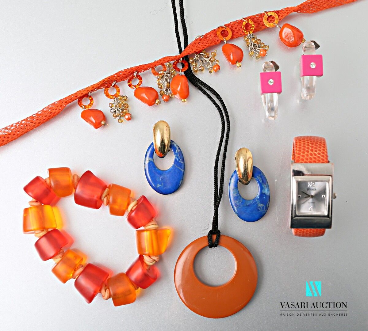 Null 一批金属、塑料和各种材料的花式珠宝，包括一条带橙色流苏的项链，一条带橙色环的弹性线的手链，一个支持棕色环的吊坠，一对仿青金石的耳夹，一对支持半透明环的&hellip;