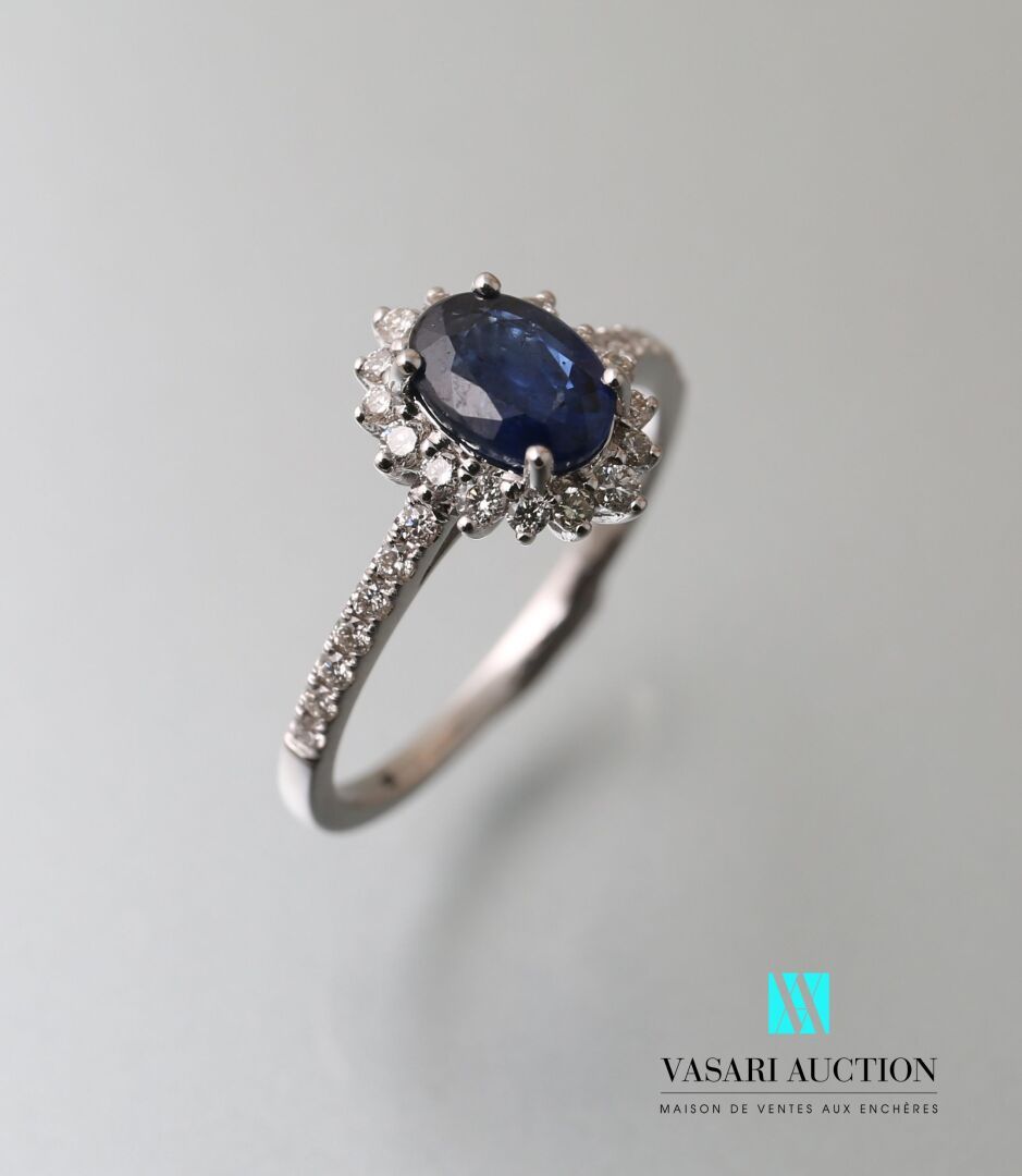 Null 雏菊戒指，白金75千分之一，中间镶嵌了一颗椭圆形的蓝宝石，重约1克拉，边缘和肩部有现代大小的白钻。

毛重：2.43克 - 手指尺寸：51