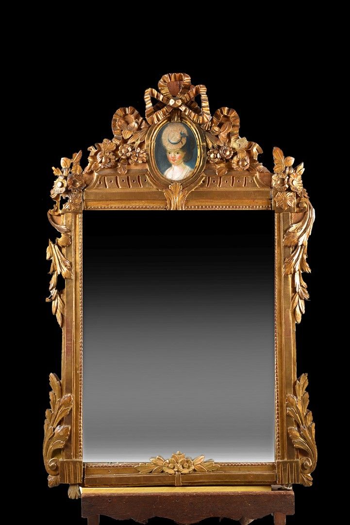 Null 一面饰有由蝴蝶结和花朵托起的奖章的山形镜，里面有一个用粉彩画的年轻女子的肖像（玻璃不见了），用木头雕刻。18世纪。尺寸115x73厘米。事故。