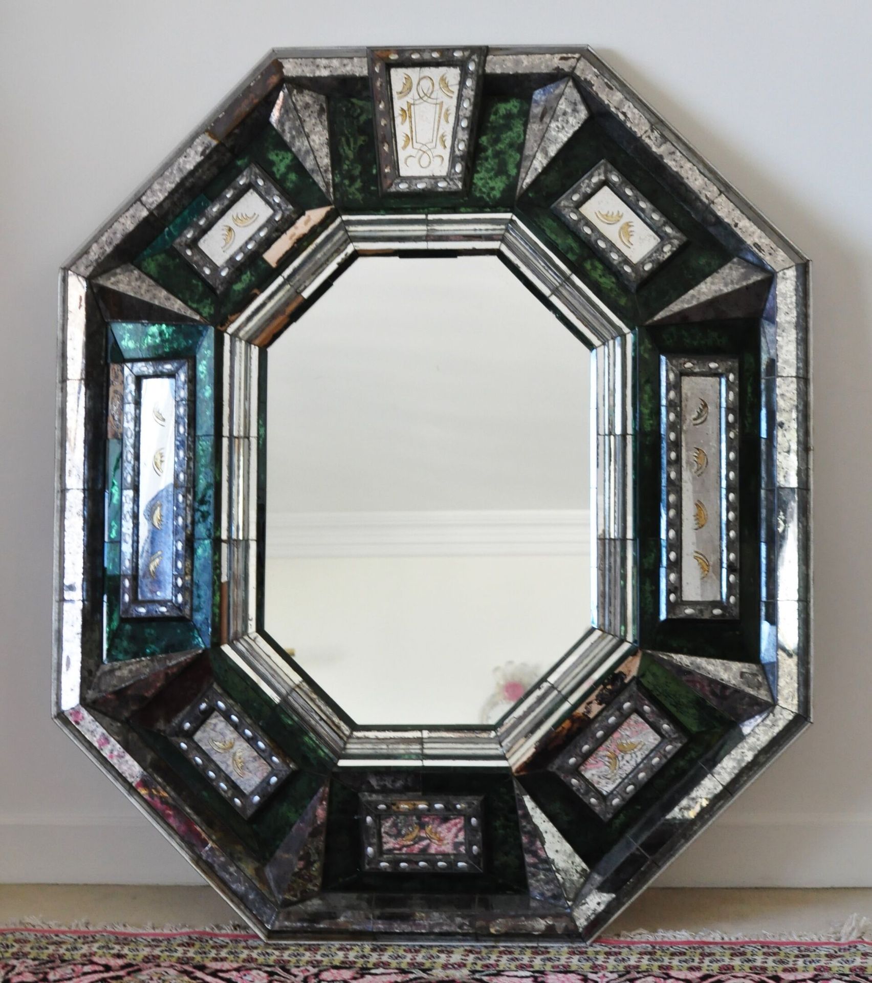 Null 大的八角形镜子，有釉珠，框架有一个凸出的装饰有几何图案的部分着色的绿色和银色的铜锈。威尼斯风格的现代作品。

尺寸：130 x 110 cm

(小姐&hellip;