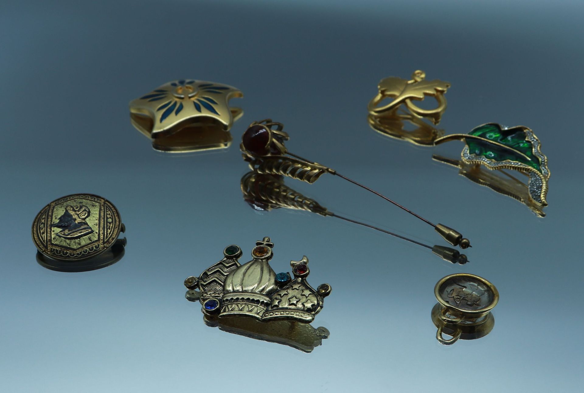 Null 一套鎏金金属胸针，包括:

- 一枚镀金的金属心形胸针，带有树叶设计。尺寸：3,5 x 4 cm

- 一枚以金属和玻璃的宗教建筑为特色的胸针。尺寸：&hellip;