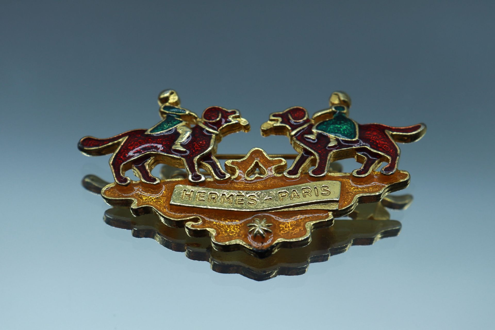 Null HERMES Paris 

Gilded metal brooch featuring two girls riding dogs in ename&hellip;