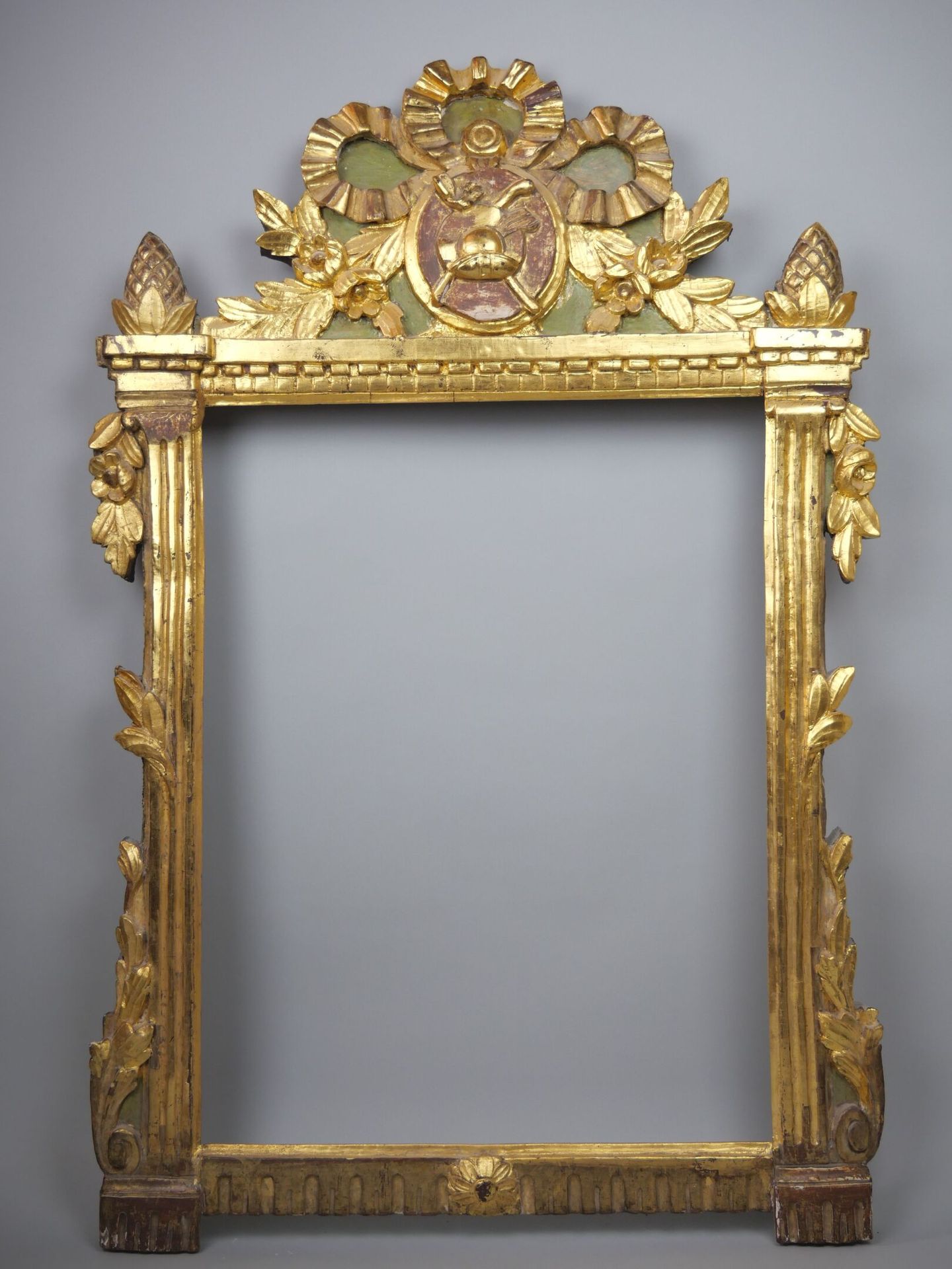 Null 雕刻和镀金的木制镜框，踏板上装饰有花园属性的奖章，顶部有一个丝带蝴蝶结，壁柱的立柱顶部有松果。

路易十六时期。

尺寸：108 x 71 cm

(&hellip;