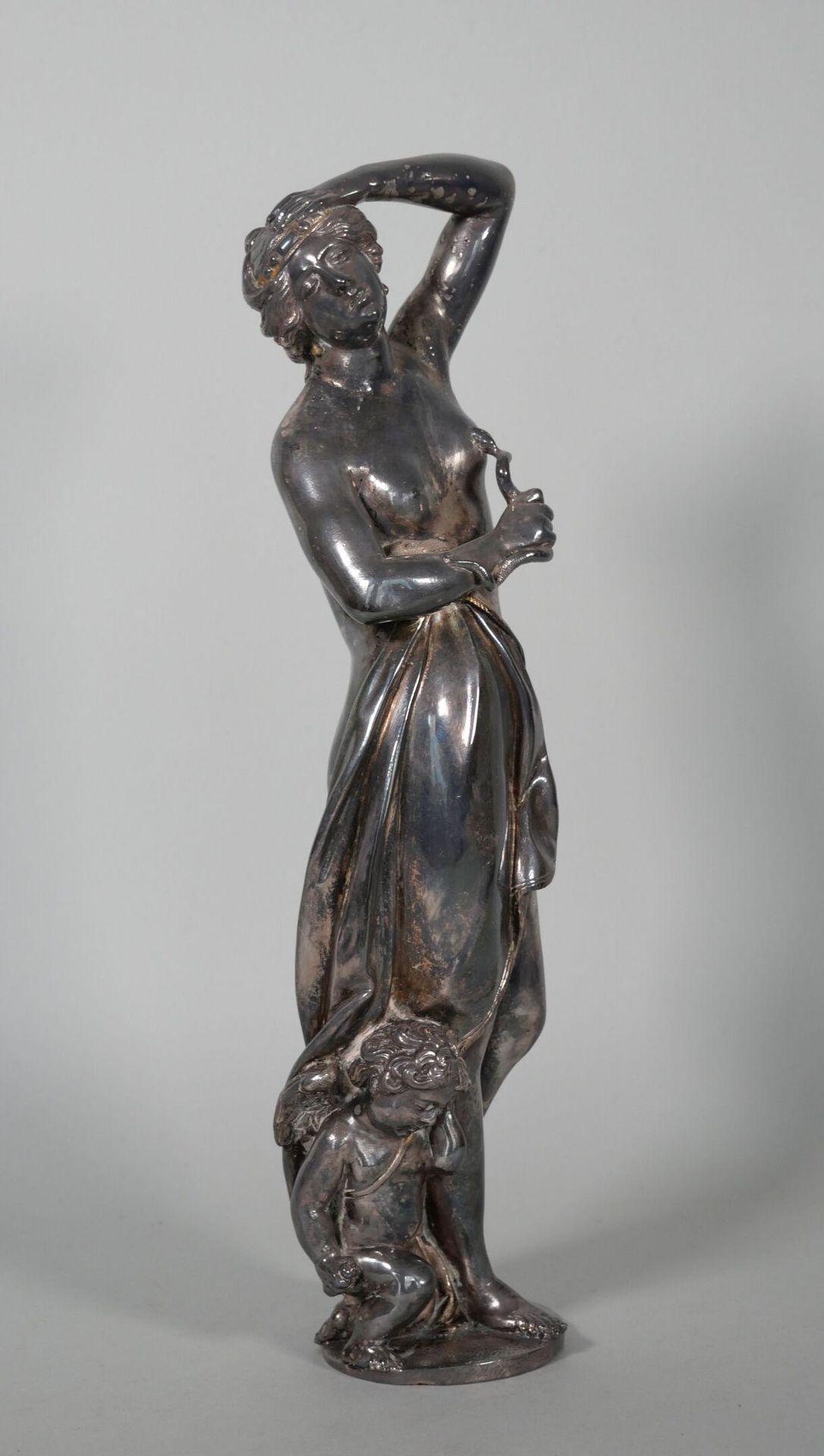 Null 银色青铜雕像，表现克利奥帕特拉抱着咬她胸部的蛇，她的脚下是一个天使。 
19世纪。
高度：31厘米 

专家 : MB ART EXPERTISES &hellip;