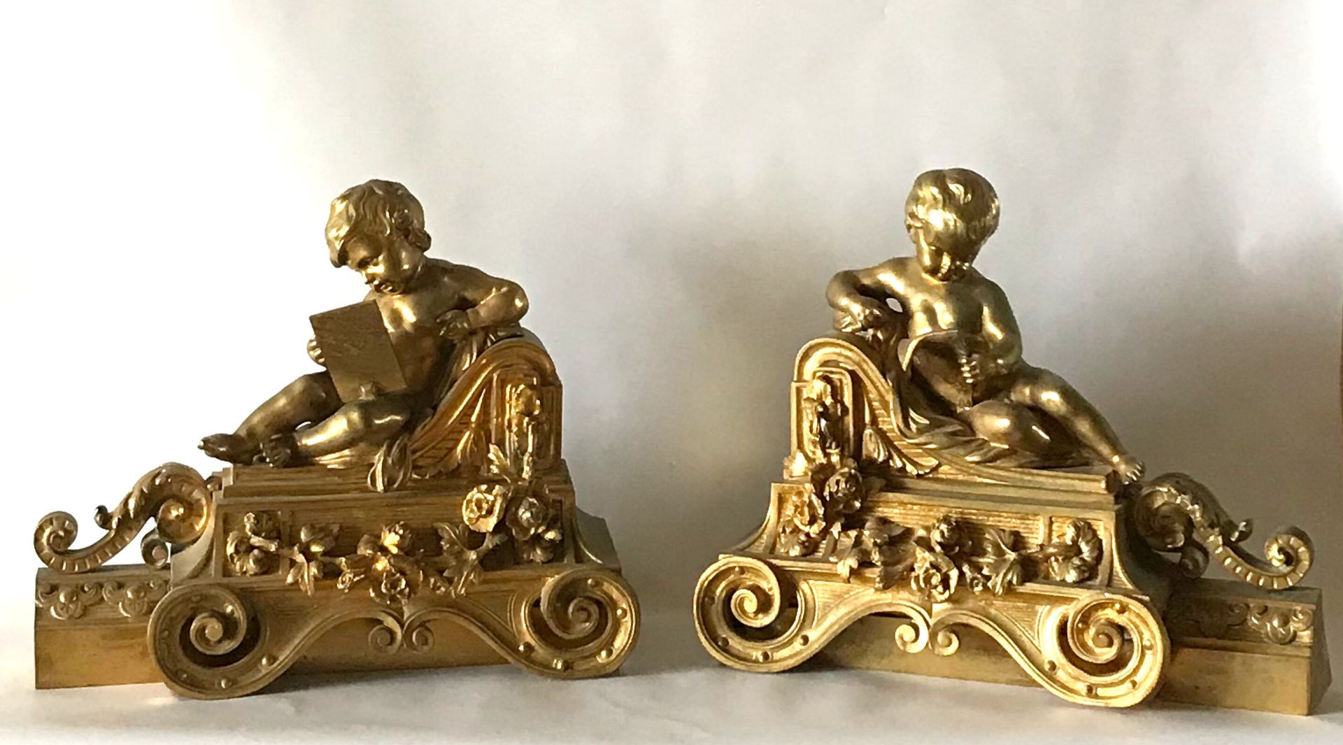 Null Pair of ormolu andirons representing two Putti reading or drawing lying on &hellip;