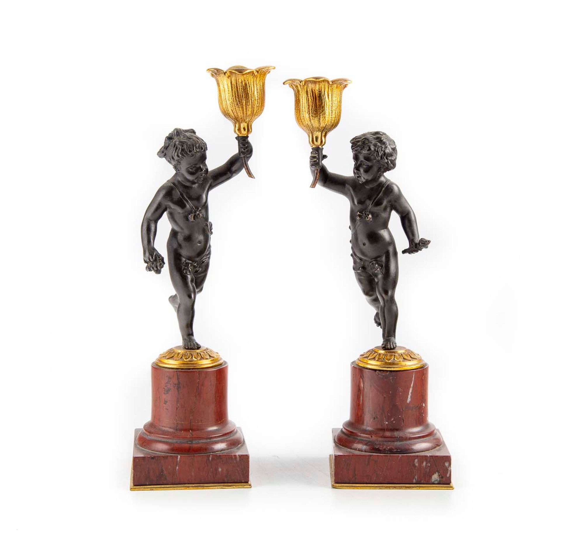 Null 一对有两种铜锈的小铜烛台，形状为手持花形灯芯的奔跑的普图，立于圆柱形红色大理石柱上

路易十六风格

H.21,5 cm