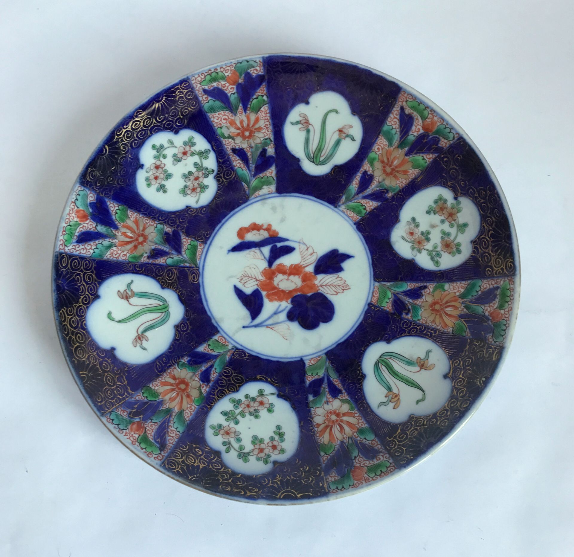 Null 日本

瓷盘上有光芒四射的装饰，背景是伊万里红、蓝和金调的花和叶。19世纪

D.28厘米