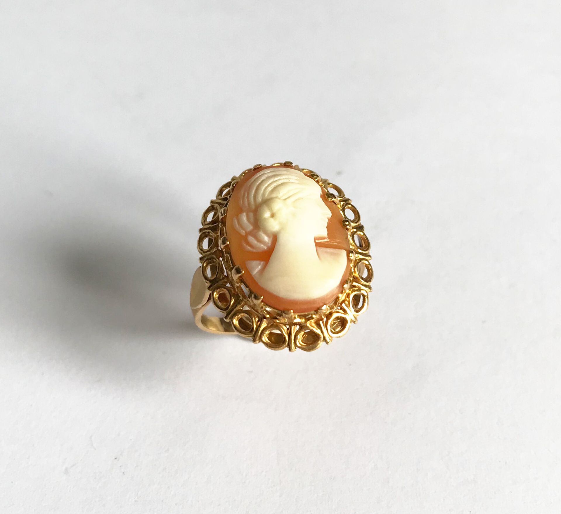 Null 镂空边框的黄金戒指，边框上装饰着一个年轻女子的浮雕轮廓。

毛重4.3克。