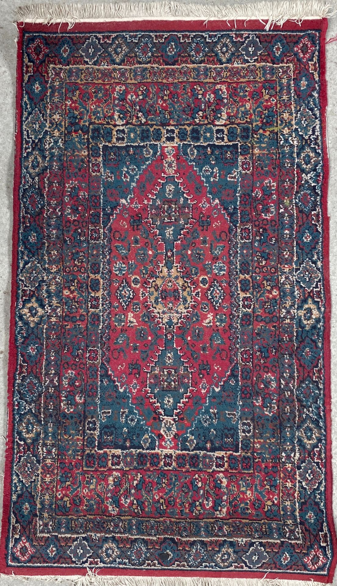 Null 羊毛地毯，中央有一个长方形的奖章，红色背景上有一个风格化的花朵图案和蓝色的边框。具有几何图案的宽边。

80 x 145厘米

磨损的