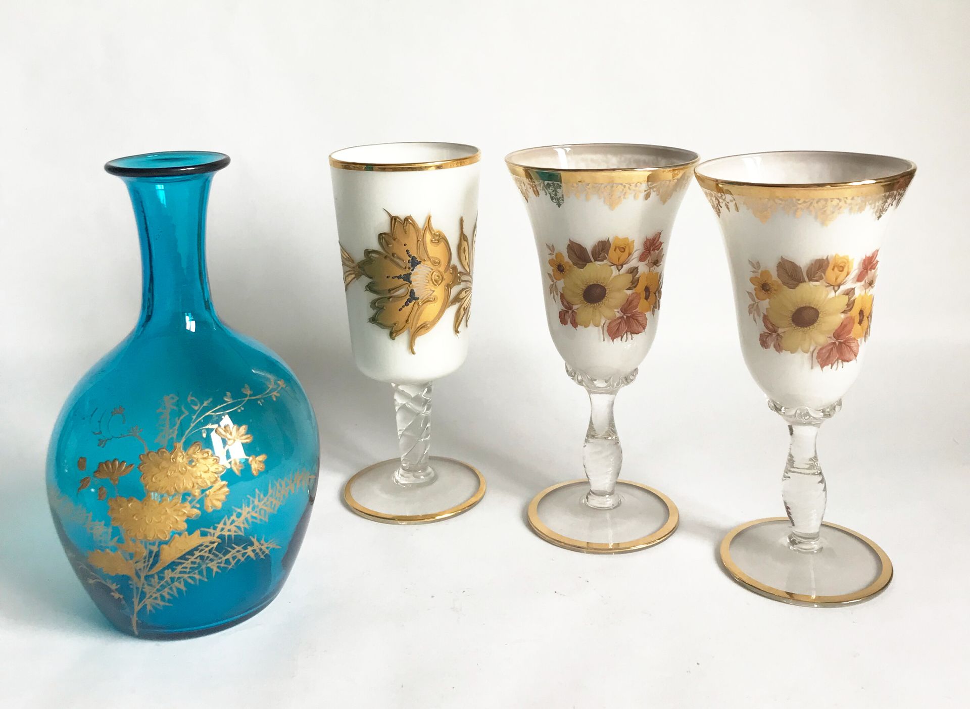 Null 一套三只有柄玻璃杯，白色乳白色背景上有珐琅花，还有一只蓝色玻璃杯，上面有镀金的装饰（瓶塞不见了）。