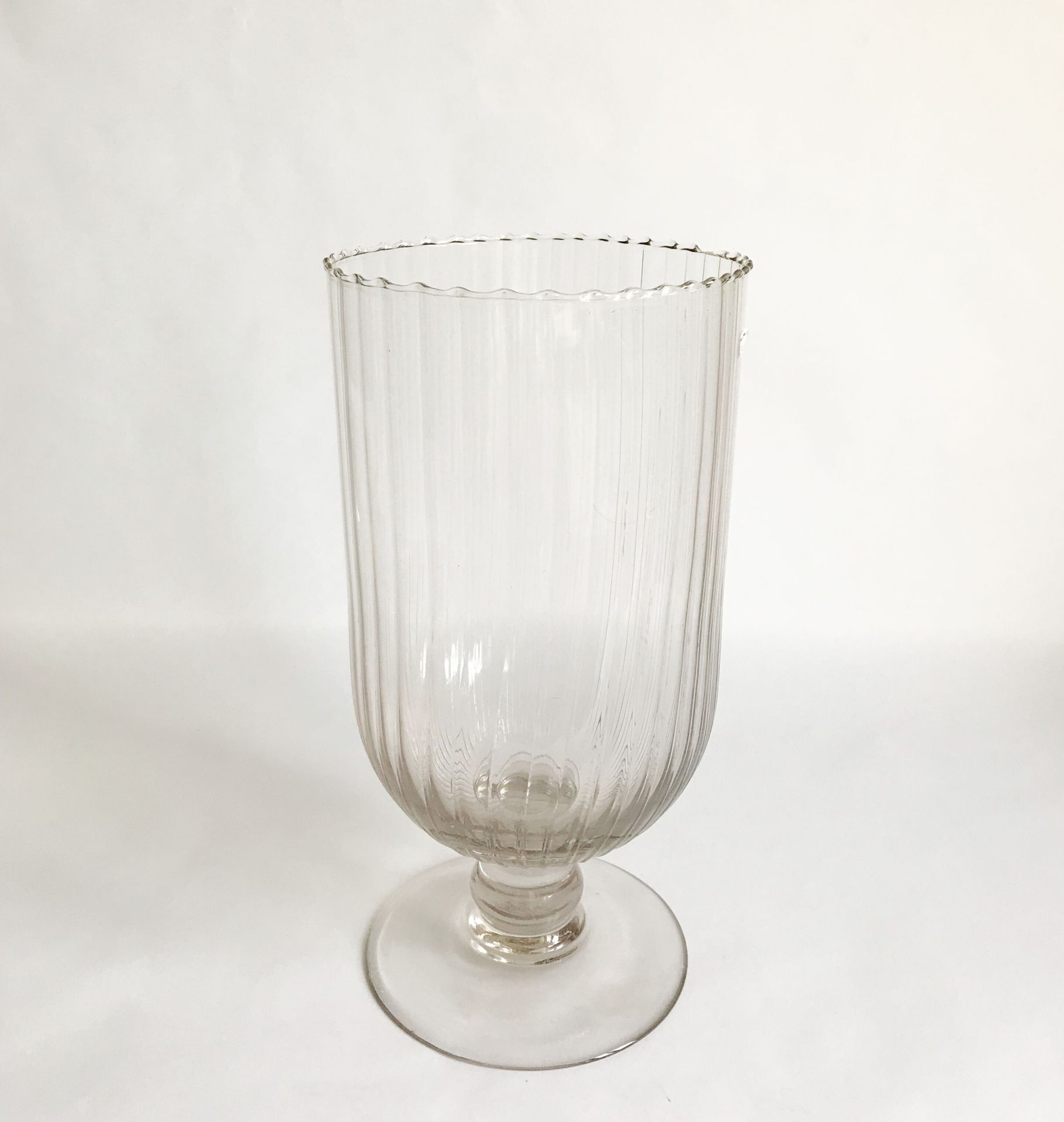Null 一个大型的吹制玻璃花瓶，放在基座上，边缘有棱纹。

H.34厘米

边缘有轻微的缺口