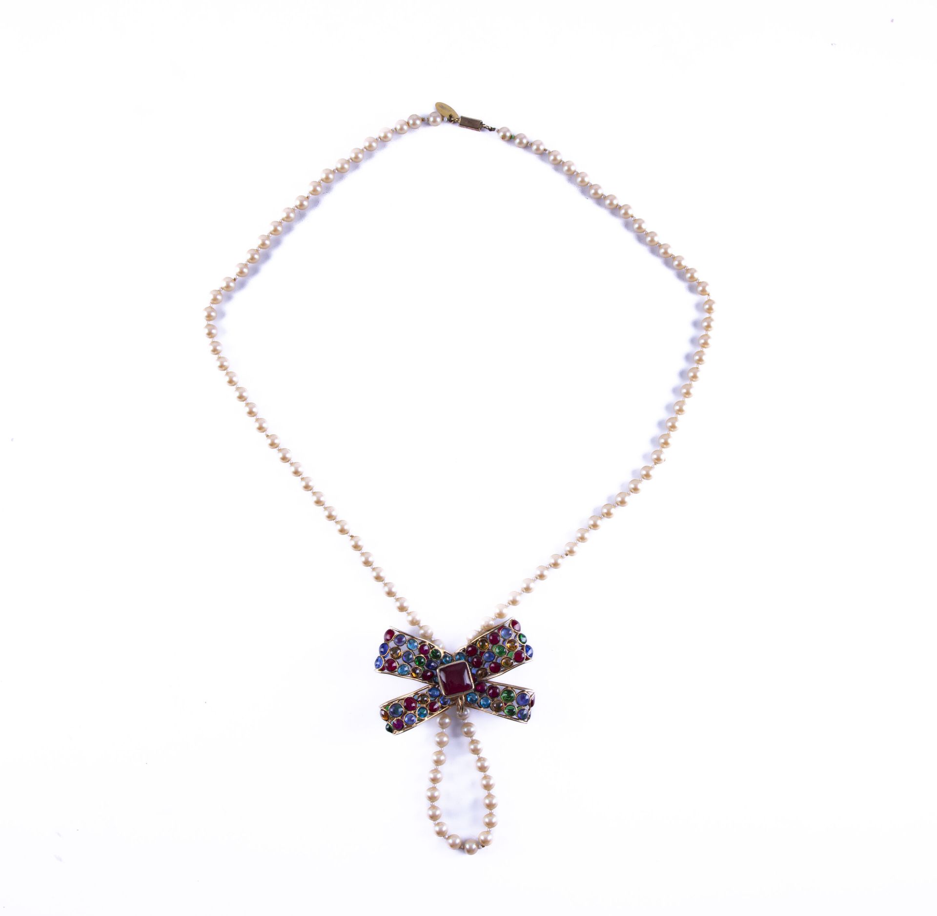 Null Sautoir en fausse perles orné d'un pendentif en forme de noeuds. 
L. : 52 c&hellip;