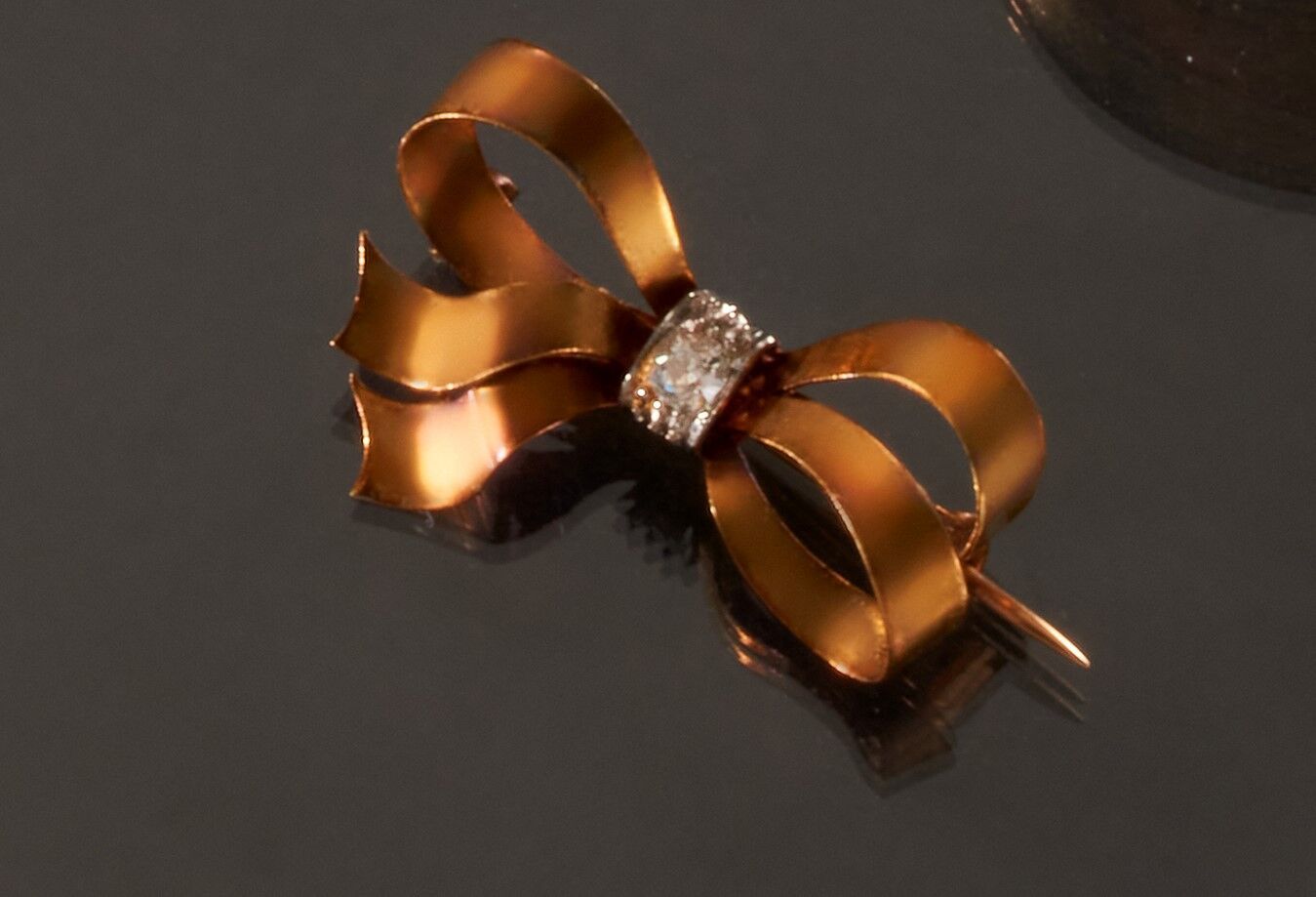 Null 750千分之一的黄金胸针结，中心装饰有一颗古代大小的圆形钻石。
(有氧化的痕迹，可能错过了一部分)
长度 : 3厘米
总重量 : 3,4 克