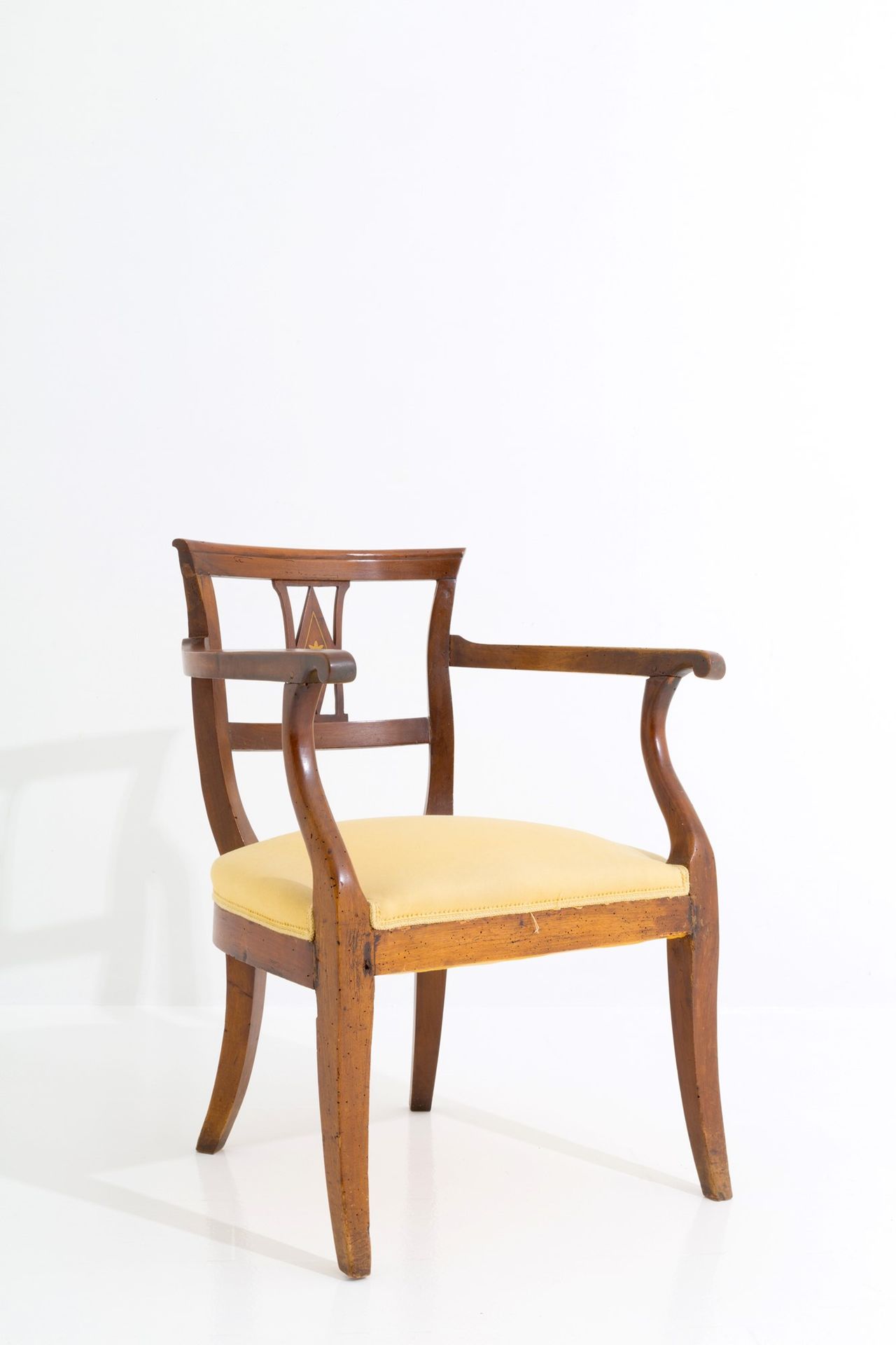 Armchair with perforated backrest 胡桃木扶手椅，弧形穿孔椅背，镶嵌黄铜，马刀腿和软垫座椅。19世纪初。