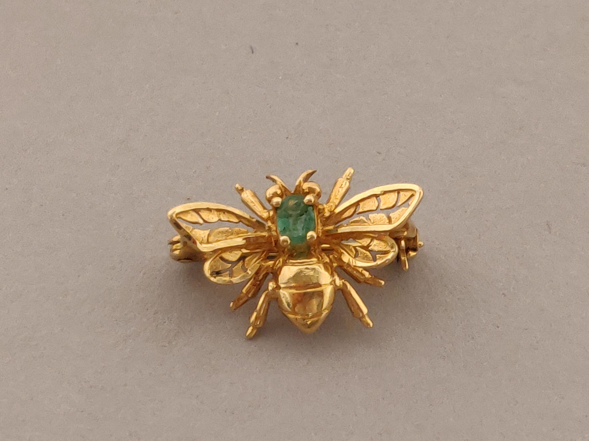 Null 黄金（750/°°）蜜蜂形状的胸针，镶嵌有绿色宝石。毛重：2.2克。宽度：1.8厘米。