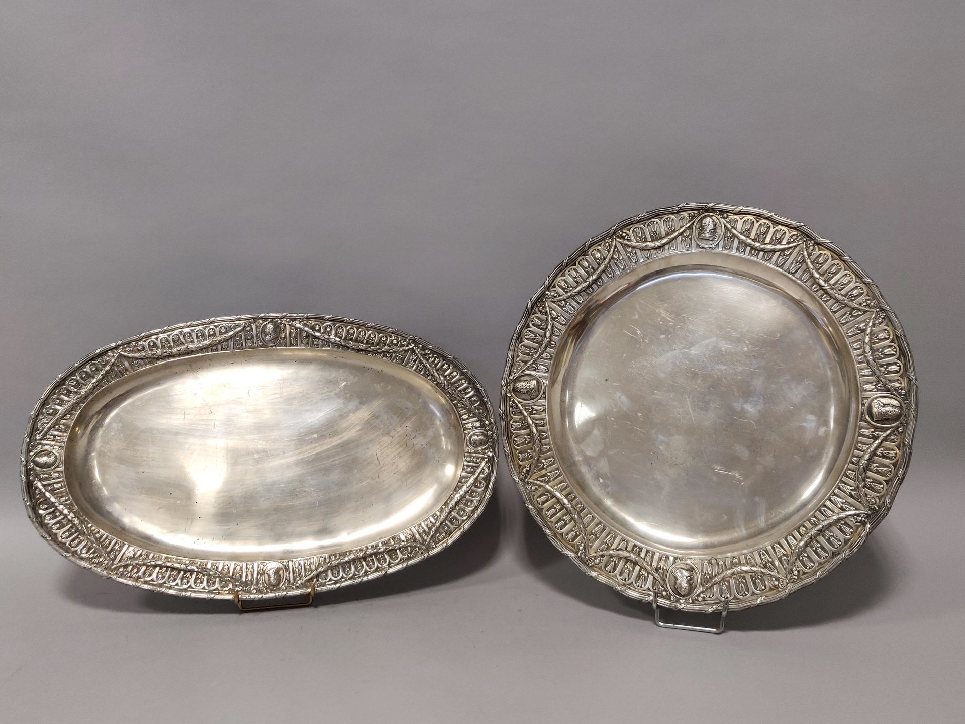 Null 两个路易十六风格的银盘，装饰有皇家轮廓的奖章，由月桂花环连接，一个圆形，另一个椭圆形。花哨的标志。总重量：约2.8公斤。尺寸：圆形（直径43厘米），椭&hellip;