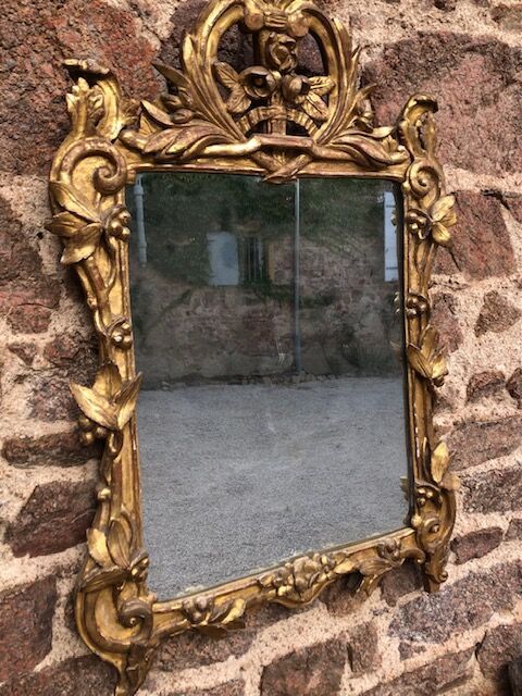 Null 一面雕刻和镀金的木质镜子，有一个叶子框架和一个镂空的花束的花架。

18世纪，罗纳河谷。

H.90 cm - L. 61 cm。

事故，修复。