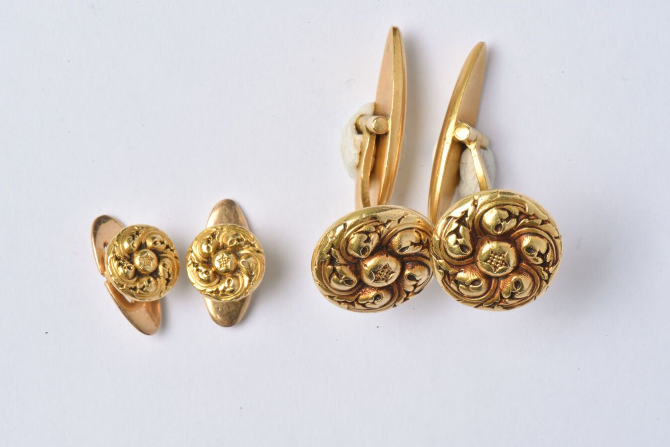 Null 镶嵌于18K黄金（750/oo），包括一对带有圆形植物图案和光滑脐带的铰接式袖扣和一对带有图案的礼服纽扣。毛重：12.7克。