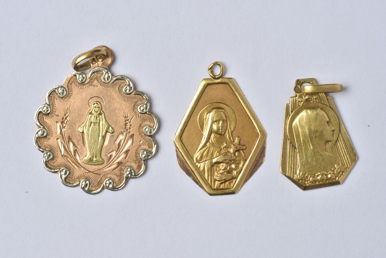 Null 18K(750/oo)金拍品包括3枚圣母宗教纪念章，其中两枚是专用的，背面有日期（1924年和1935年）。托架有轻微变形。毛重：5.6克。