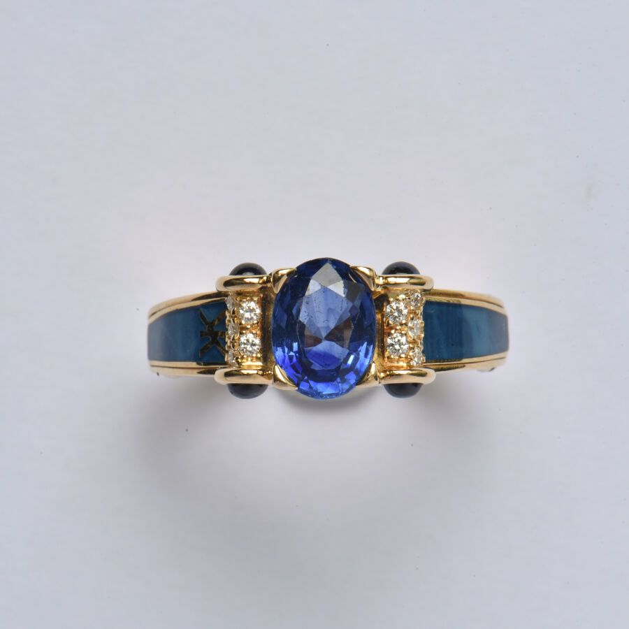Null KORLOFF：18K（750/oo）黄金戒指，以一颗重约1.50克拉的椭圆形蓝宝石为中心（可能经过处理），卷轴图案镶嵌明亮式切割钻石，并以凸圆形蓝宝&hellip;