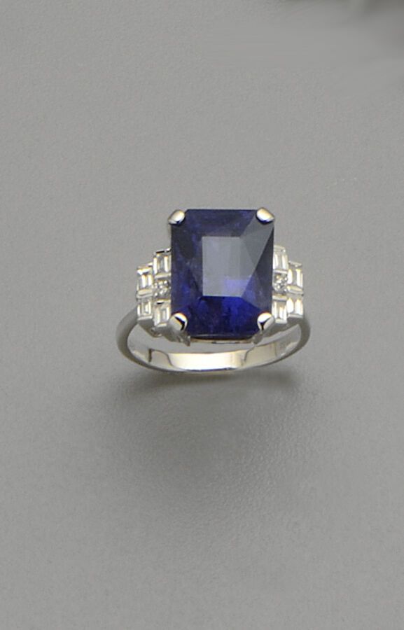 Null 18K(750/oo)白金戒指，以一颗重达10.51克拉的大型矩形切割蓝宝石为中心，未经热处理，略有 "变色"（轻微齐平裂纹），镶嵌着层层叠叠的长方形&hellip;