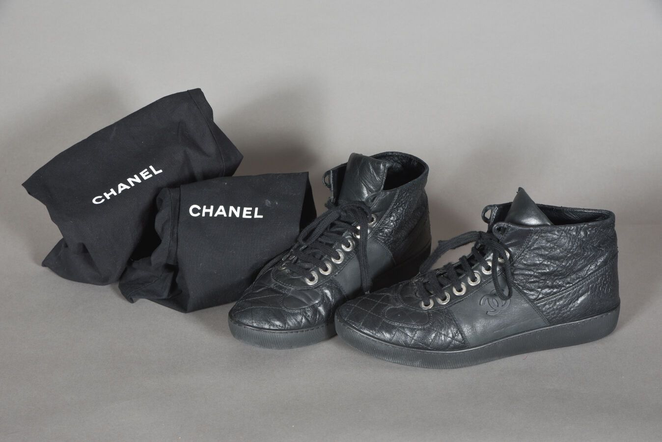 CHANEL. Pair of black quilted leather high-top sneakers,…