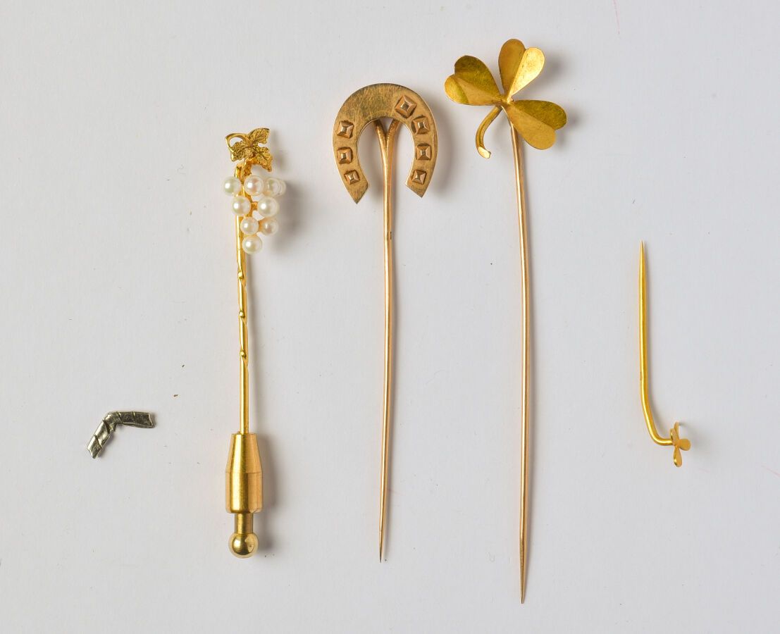 Null 18K（750/oo）黄金拍品包括一个马蹄形领带针、一个三叶草领带针和一个三叶草围巾针。毛重：4.6克。
我们附上一个镀金的金属领带针，上面有一串葡萄&hellip;