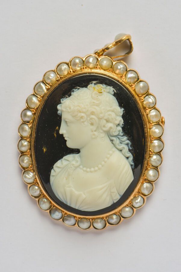 Null 一枚18K(750/oo)黄金胸针，在双色玛瑙上浮雕了一个女人的半身像，周围和扣子上装饰着半颗珍珠。19世纪。尺寸：46 x 38毫米。背面和头发顶部&hellip;