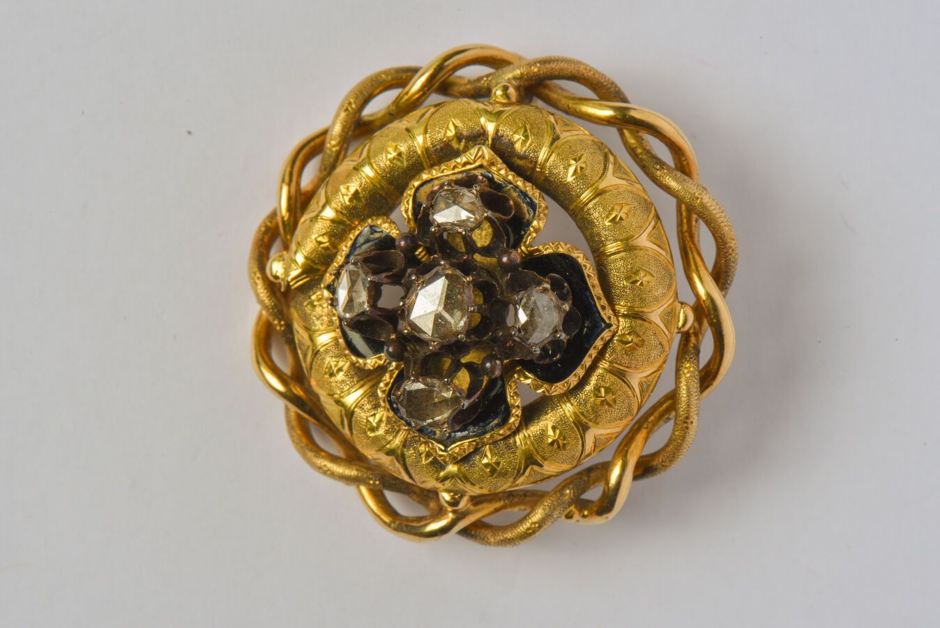 Null *古董18K（750/oo）黄金镂空玫瑰胸针，中心是黑色珐琅图案上的五颗玫瑰式切割钻石（缺失和重做），镶嵌物上有扭曲的金属丝装饰。背面有事故和锡焊接的&hellip;