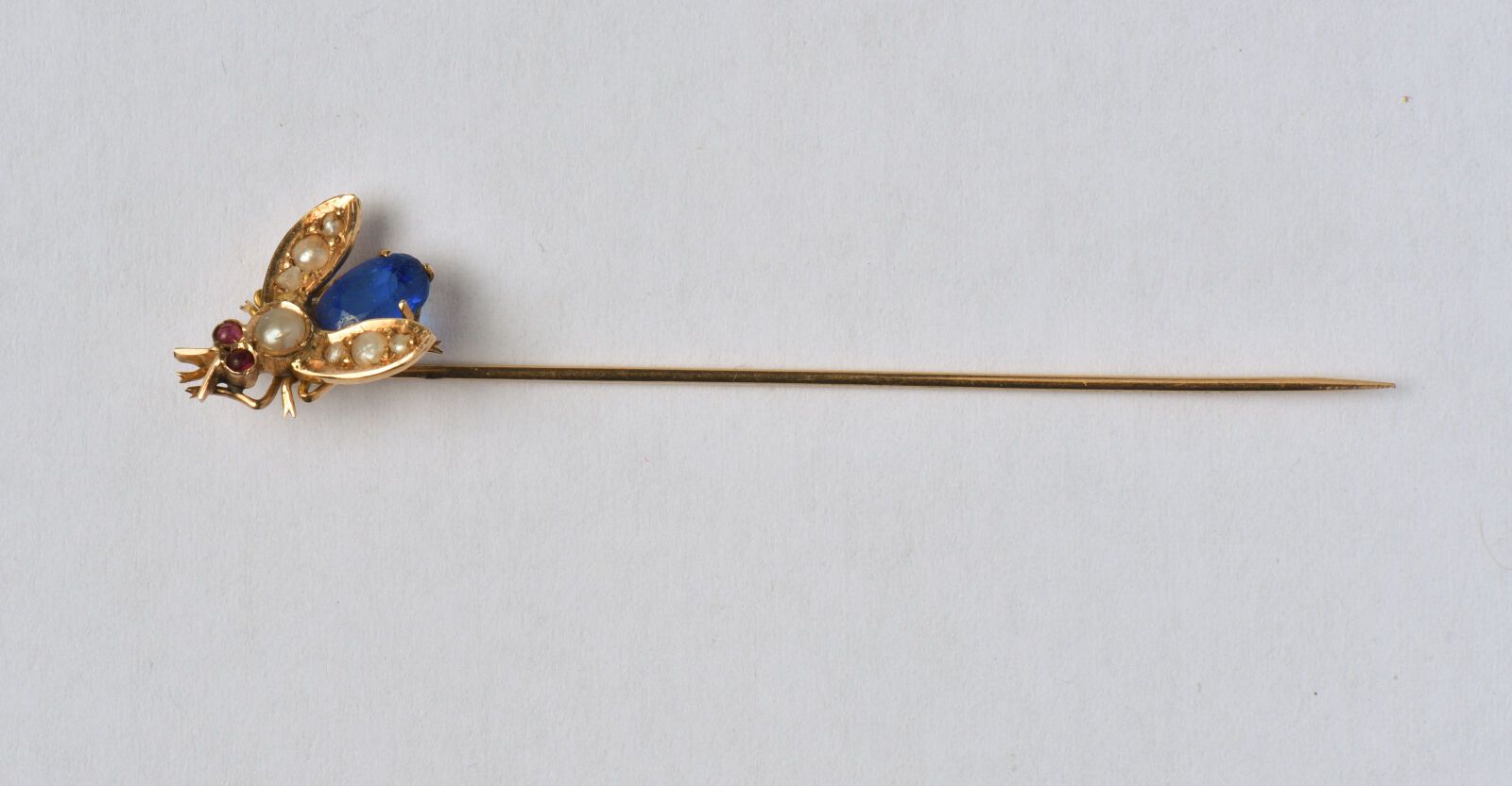 Null 18K（750/oo）黄金领带针，设计（重绕）描绘了一只镶嵌有半颗珍珠的苍蝇，眼睛为凸圆形红色宝石，腹部为蓝色玻璃。毛重：1.2克。