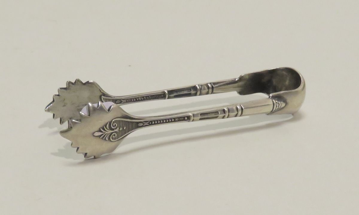 Petite pince à sucre en métal argenté. Long : 10 cm.