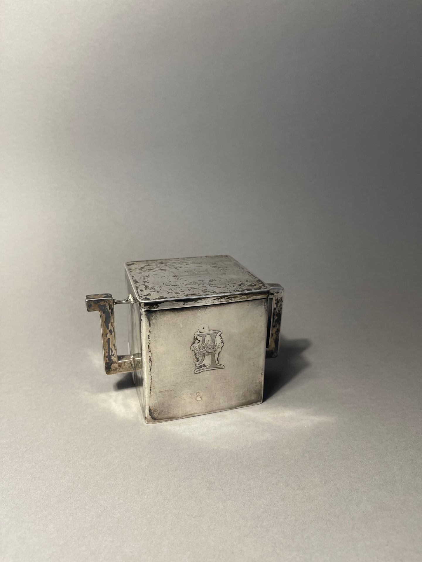 Null 一套银质旅行茶具，包括一个风格化的方形茶壶，壶嘴是手柄的形状，象牙配件，它用铰链打开，里面有一个两格的铰链茶盒，有吊环。整体刻有一个可能是伯爵皇冠下的&hellip;