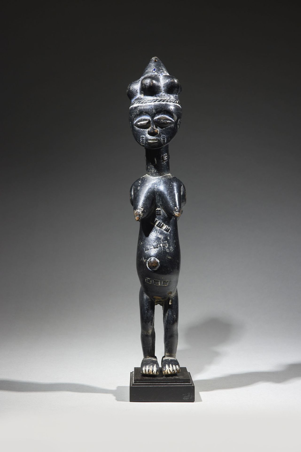 Null Kulango雕像
象牙海岸
木头和颜料
高42.5厘米
罕见的雕像，表现一个站立的女性形象，双臂交叉在背后，胸部下垂，肚子上有伤痕装饰，肚脐突出。圆&hellip;