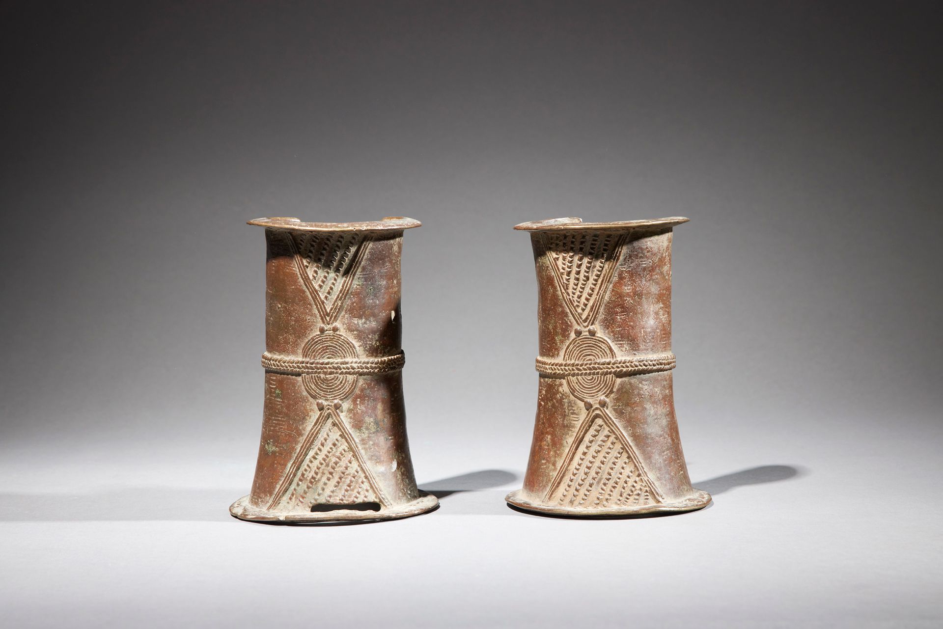 Null 一对Gurunsi脚链

布基纳法索

铜质

H.每个15.2厘米



Gurunsi青铜脚镯一对，形状为喇叭形的圆柱体。表面上出现了浮雕式的几何&hellip;
