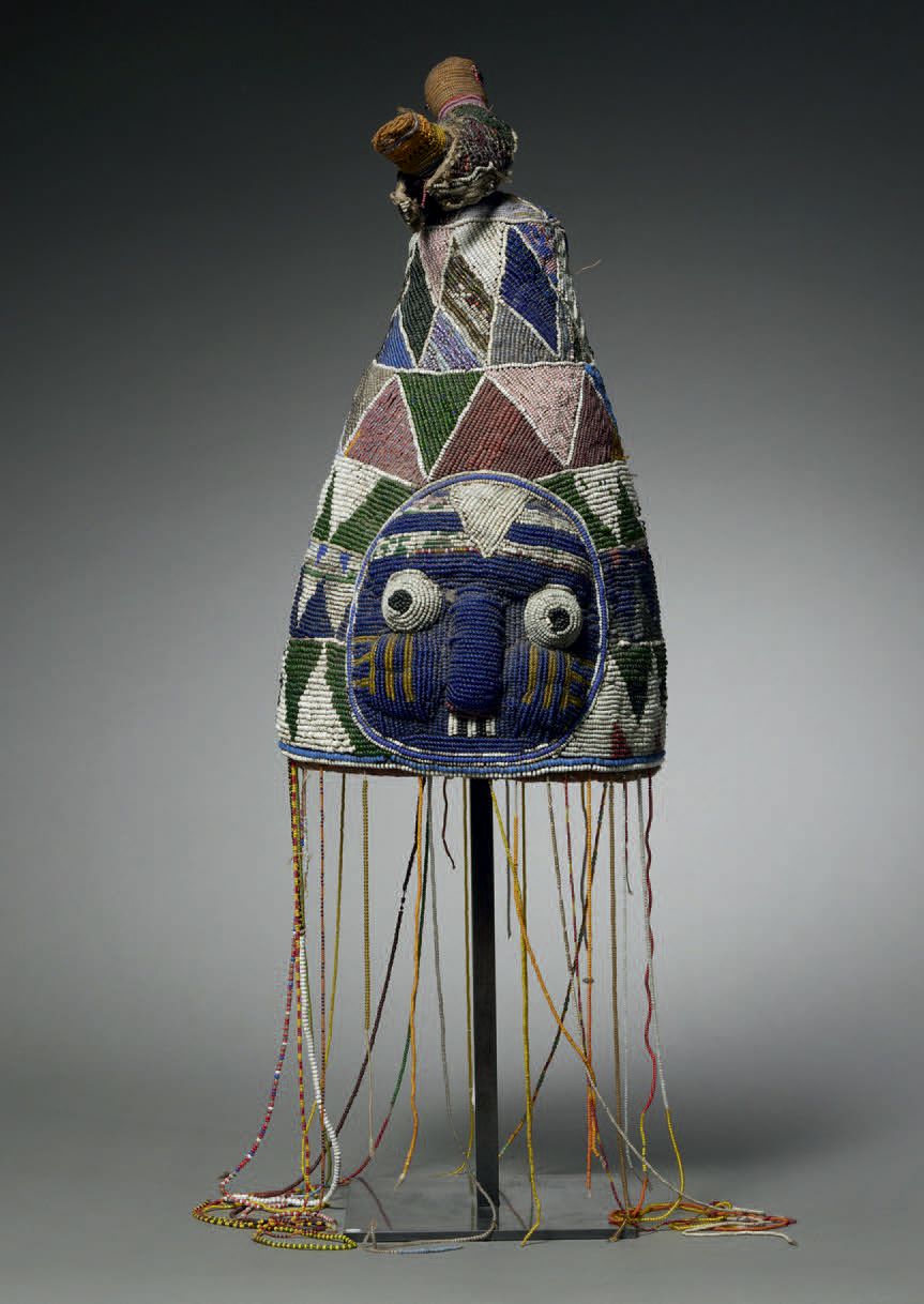 Null 约鲁巴珠子头饰
尼日利亚
纺织品，珠子 高40厘米（不含吊坠）
约鲁巴珠子头饰，有两张拟人化的脸。它的顶部是一只鸟的代表。表面完全覆盖着几何形状和颜色&hellip;