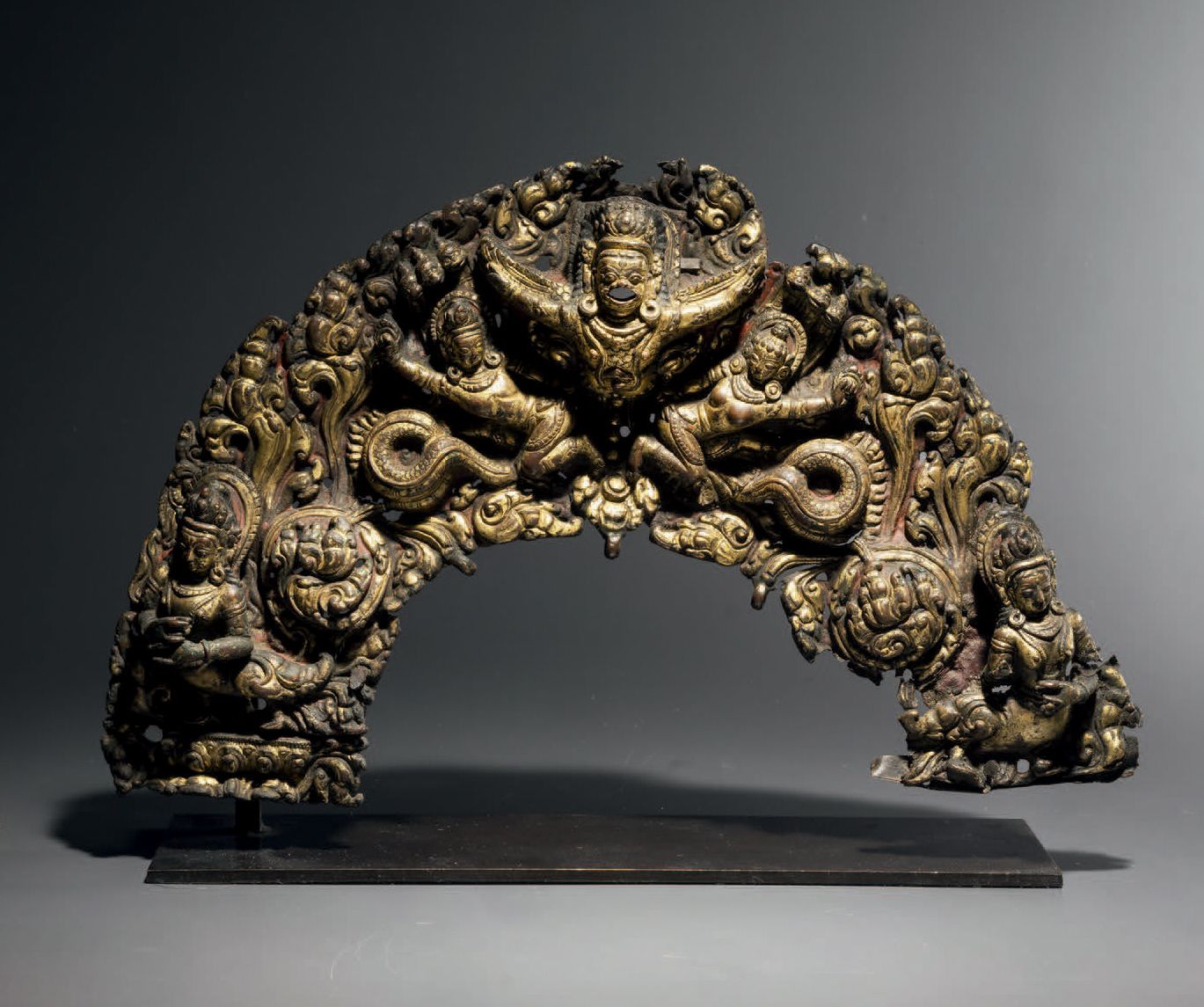 Null 托拉纳，尼泊尔，约15世纪，长19厘米。压花和镀金的铜
这是一个非常漂亮和有活力的托拉纳，充满了细节，中间是一只迦楼罗，两边是两个在树叶间的纳迦罗。两&hellip;