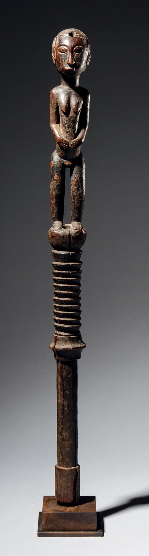Null - 巴加权杖, 几内亚
木头
H.60厘米
罕见的权杖，直柄，部分有环，顶部代表一个非常精细的站立人物。
额头顶部的一个孔可能是用来放置魔法电荷的。