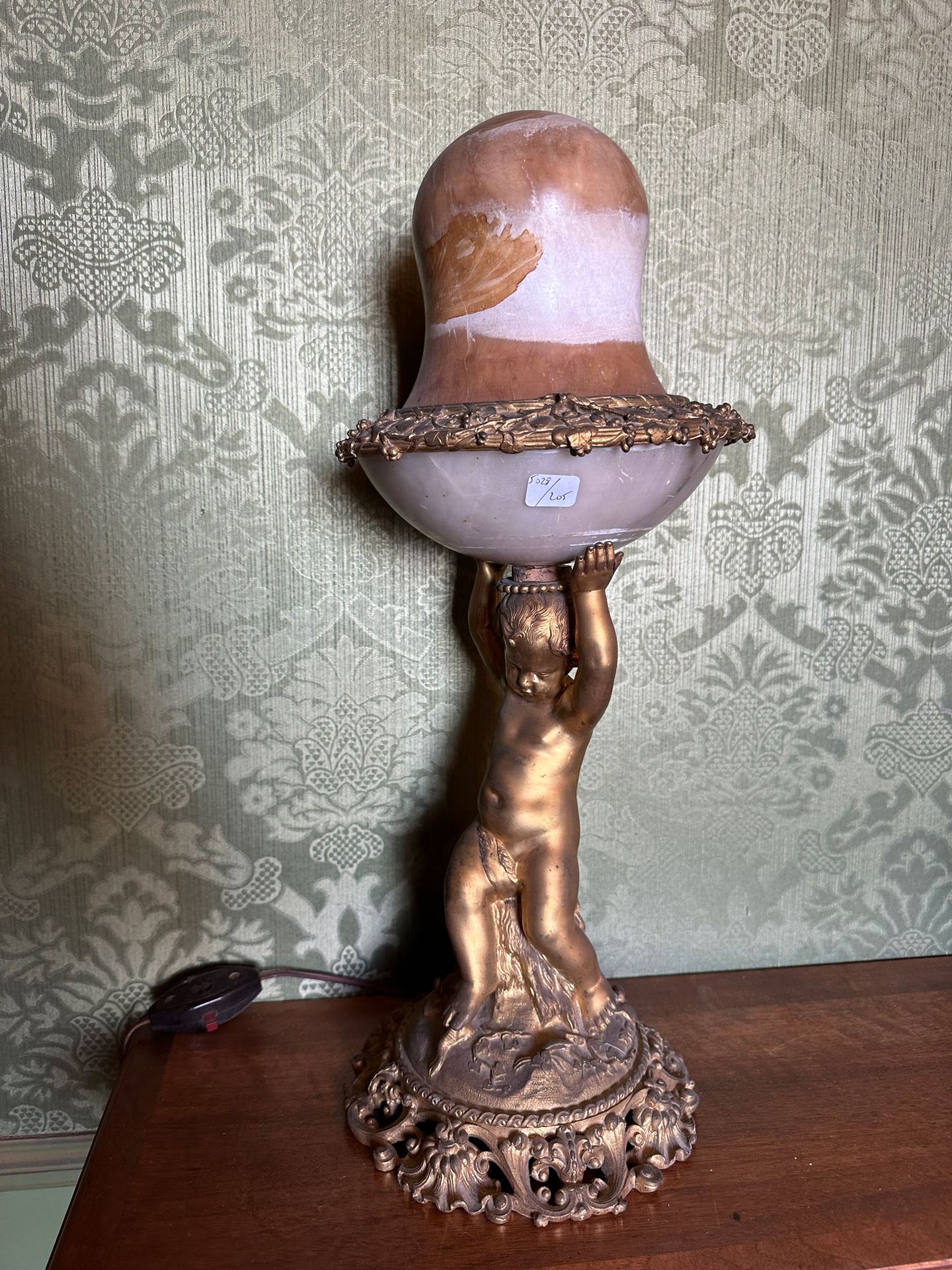 Null Lampe en bronze doré sculpté d'un putto assis sur un rocher soutenant un gl&hellip;