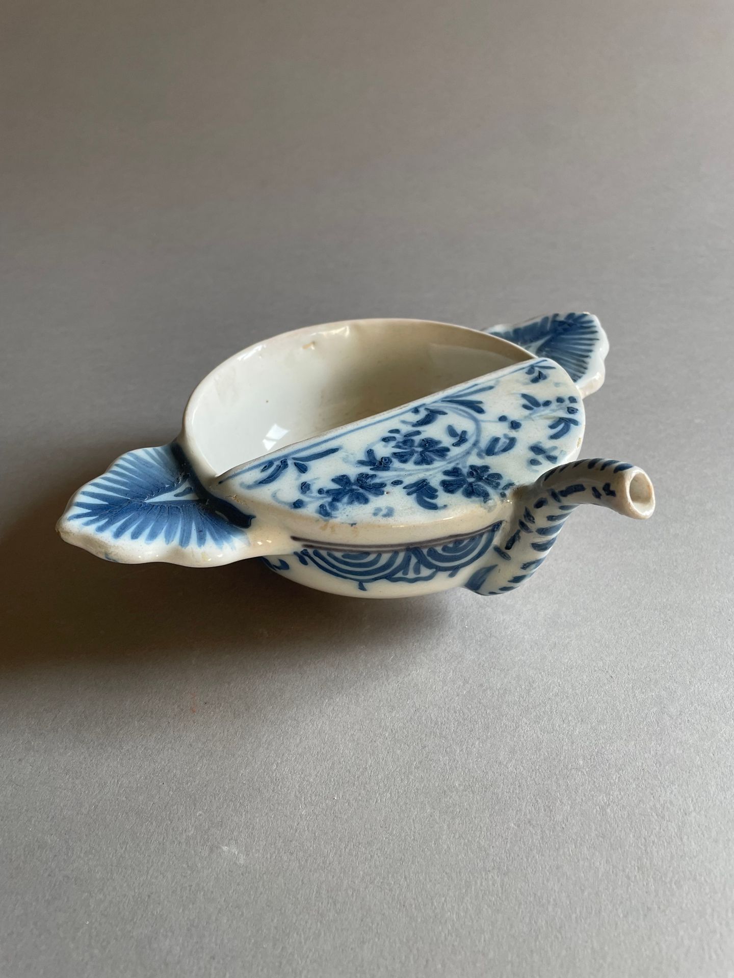 Lyon 带两侧把手的圆形病鸭，陶器，蓝色单色花枝、帷幔和梳叶装饰
18 世纪
长 23.5 厘米
(出水口修复）