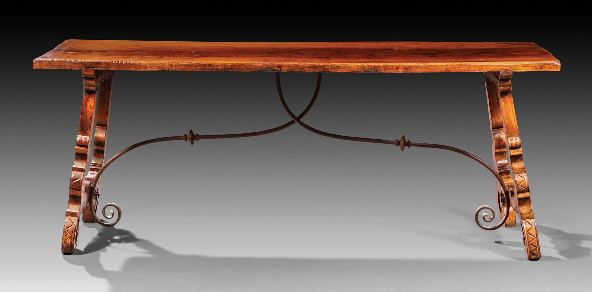 Null 胡桃木大桌，带有扇形边缘的分叉桌腿通过锻铁支架与桌面相连。
西班牙，17 世纪
H.76.5 厘米 - 203 厘米 - 66.5 厘米
虫孔