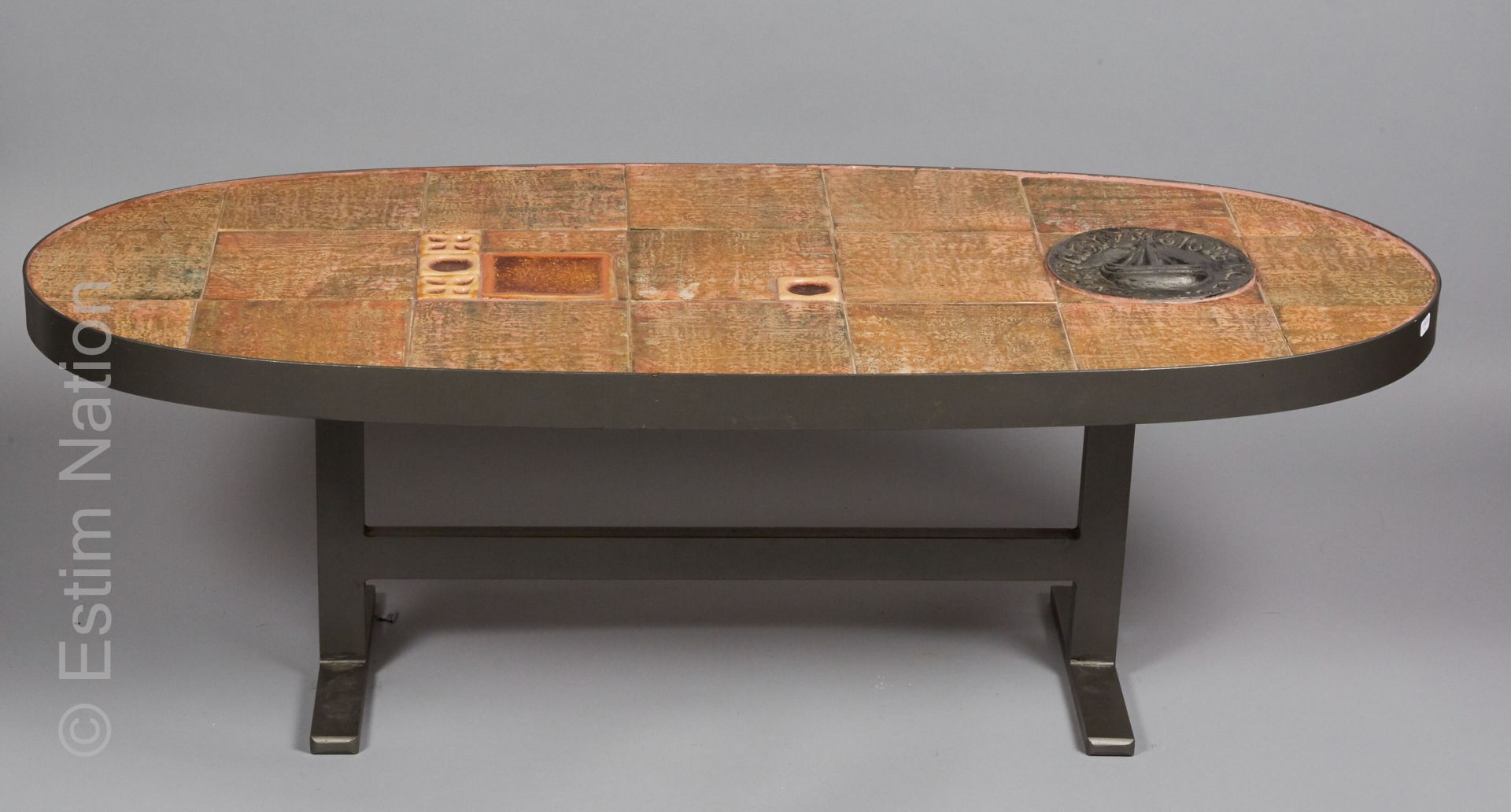 VERS 1970 - TABLE BASSE 咖啡桌，椭圆形的桌面由多色陶土砖制成，上面有熔岩上的珐琅彩，还有一个代表船的锡制护手，周围有拉丁文的铭文。197&hellip;