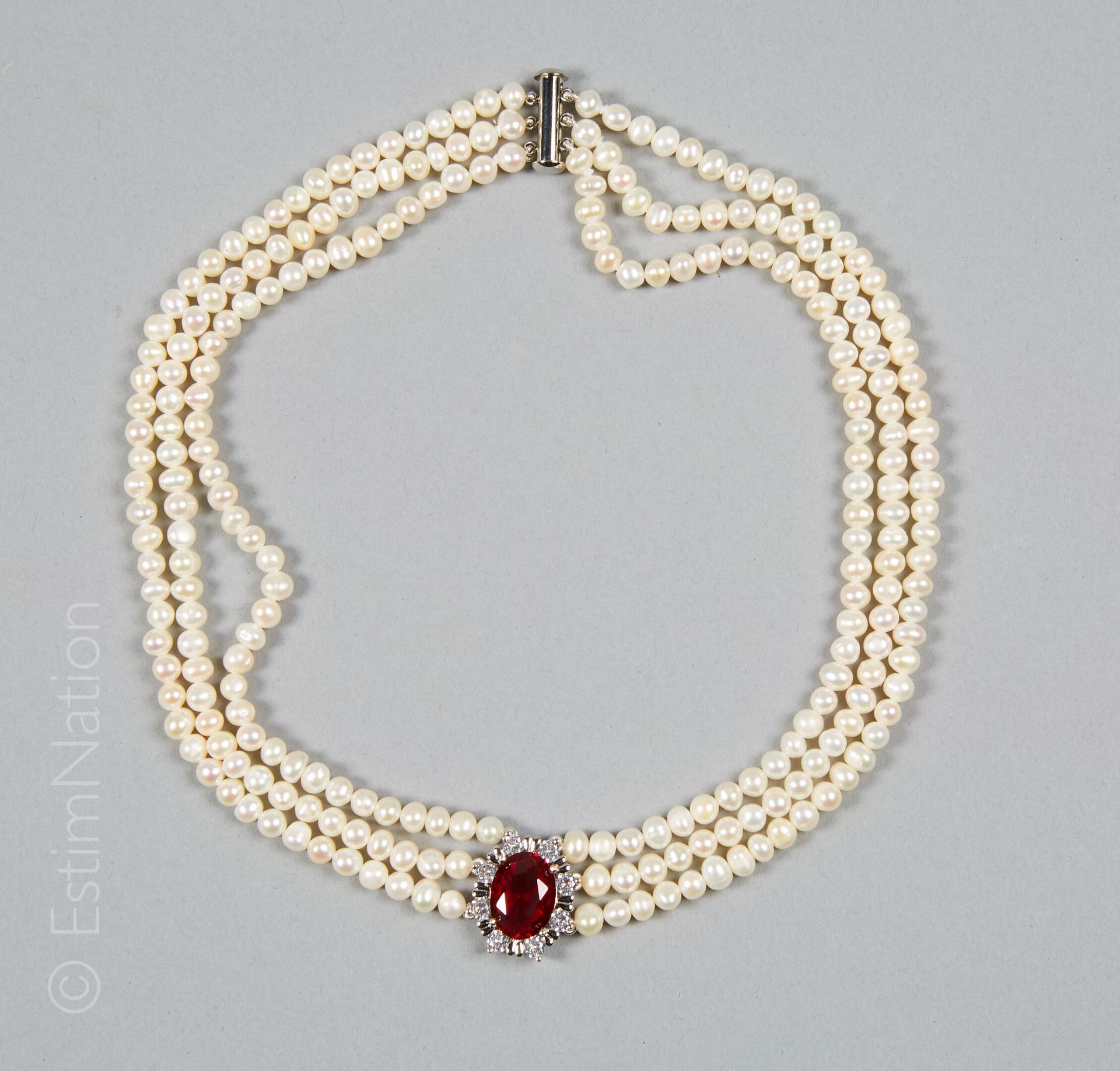 COLLIER PERLES 项链由三排淡水珍珠组成，持有一个椭圆形的图案，中心是一个刻面的红色石头，用爪子镶嵌的氧化锆。金属滑扣。

长度：41.5厘米