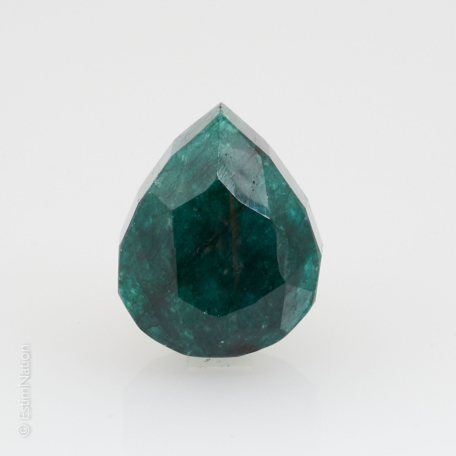 UNE ÉMERAUDE SUR PAPIER ET EXAMEN A large emerald on paper of faceted pear shape&hellip;
