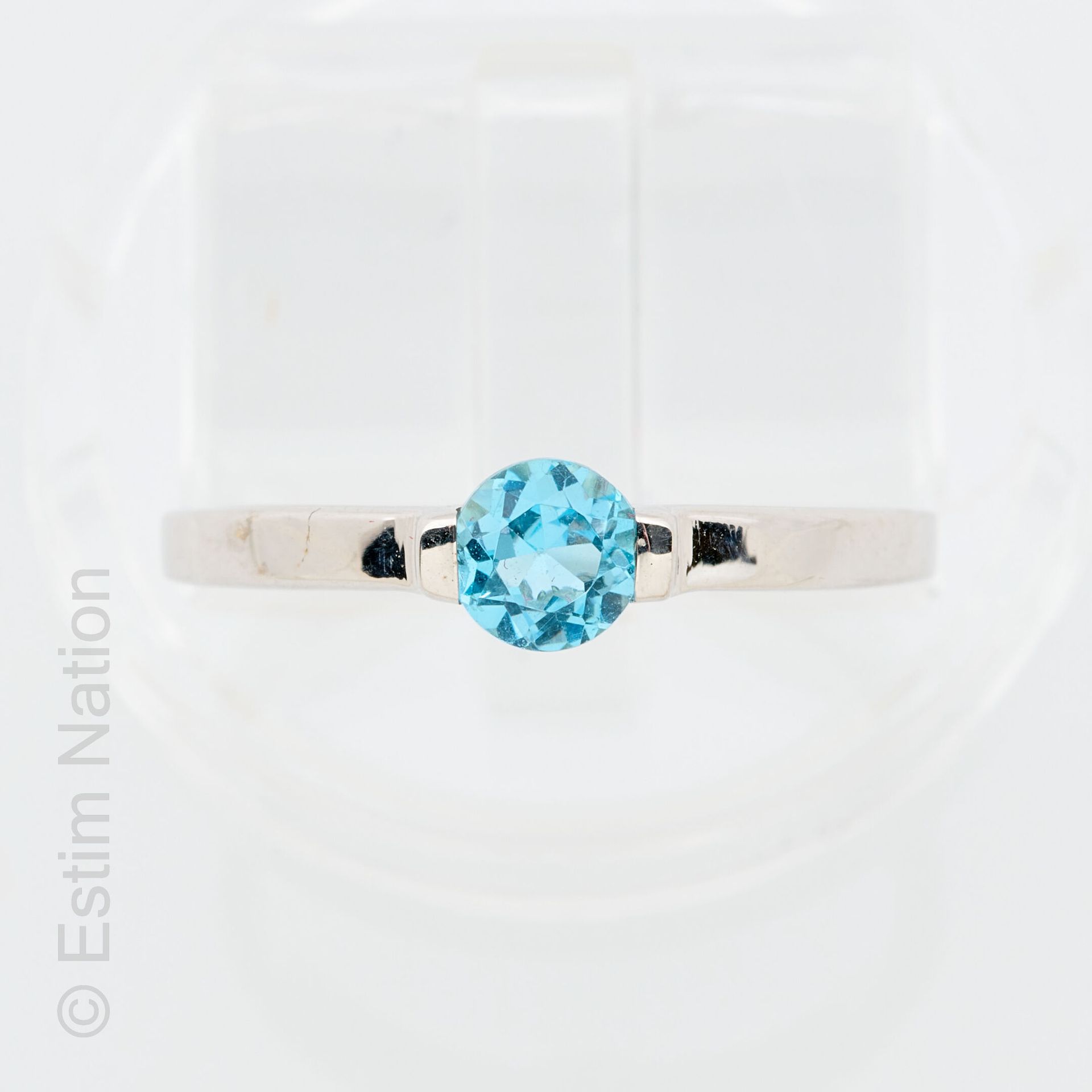 BAGUE OR TOPAZE 9K (375/°) 白金戒指，以圆形刻面蓝色托帕石为中心。 
毛重：1.62克。手指尺寸：51.5