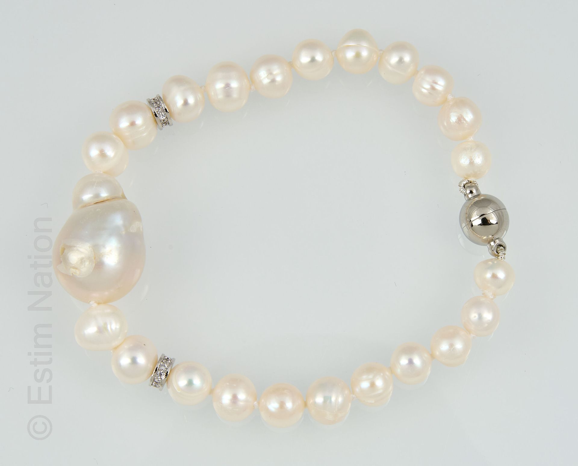 BRACELET PERLES 由淡水珍珠制成的手链，有一颗较大的珍珠，并有两个水钻环加强。磁力球扣。 
长度：18.5厘米