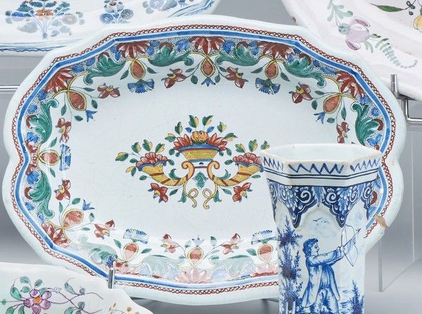 Null ROUEN，18世纪

一个椭圆形的陶器，边缘呈扇形，盆上装饰有丰饶的角，翅膀上装饰有花和叶子。

高22厘米；长30.5厘米

(Chips)